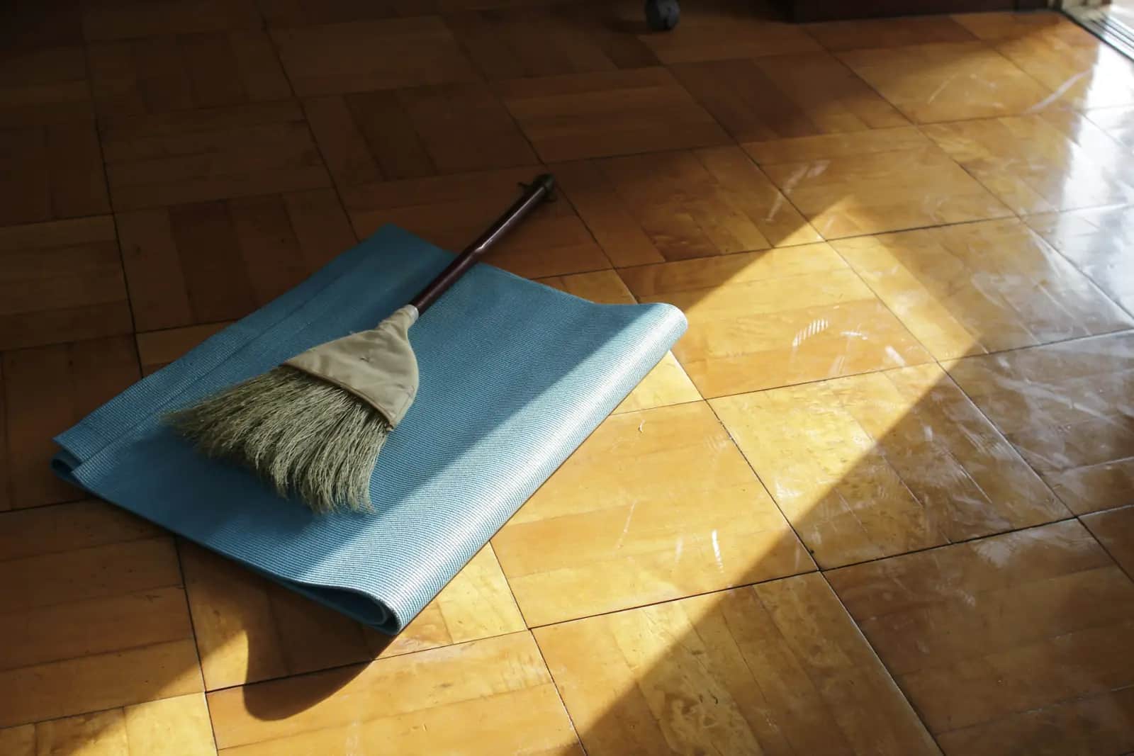 Balai et pelle posés sur un parquet au soleil