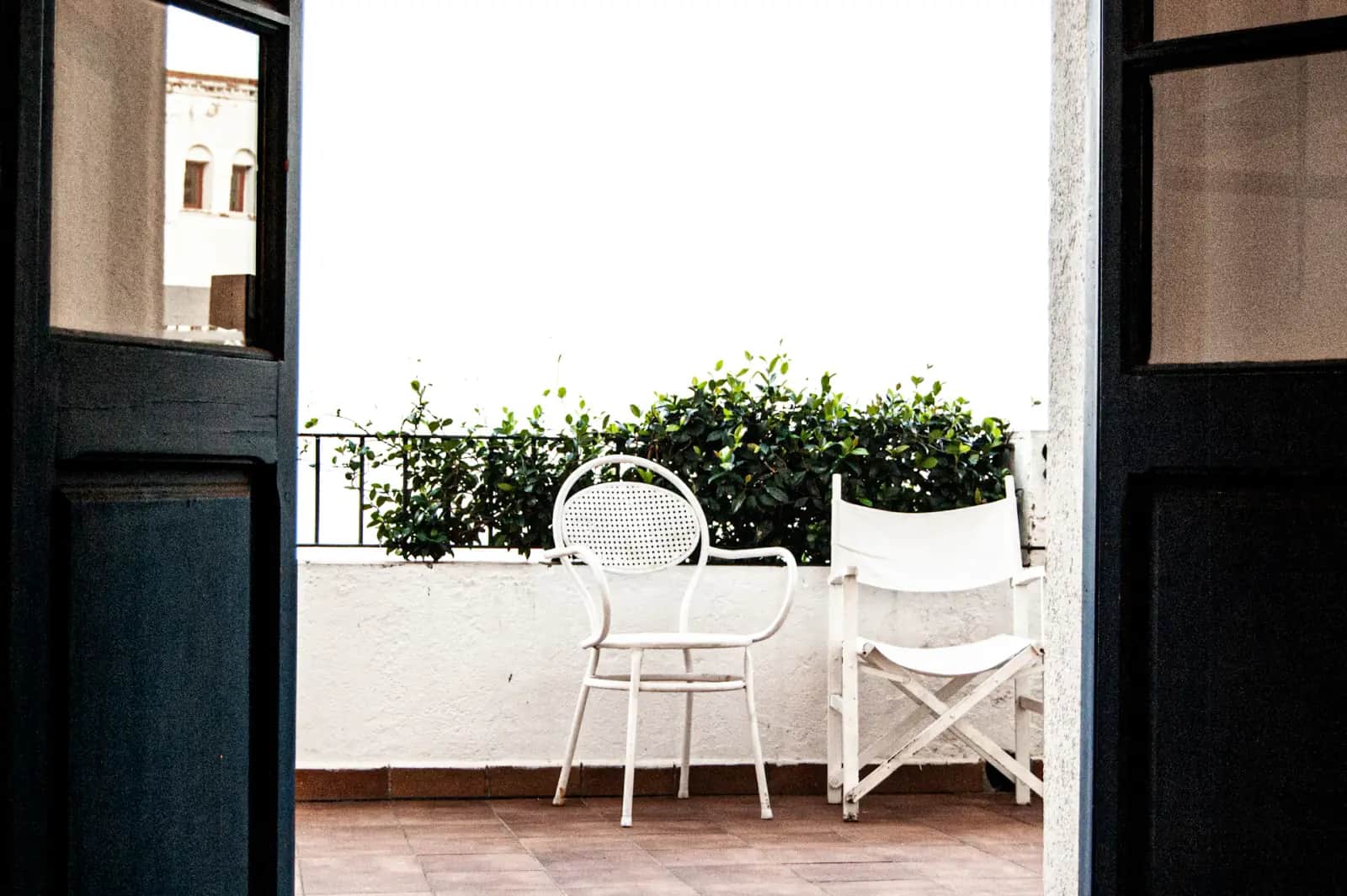 Balcon blanc avec chaises et plantes