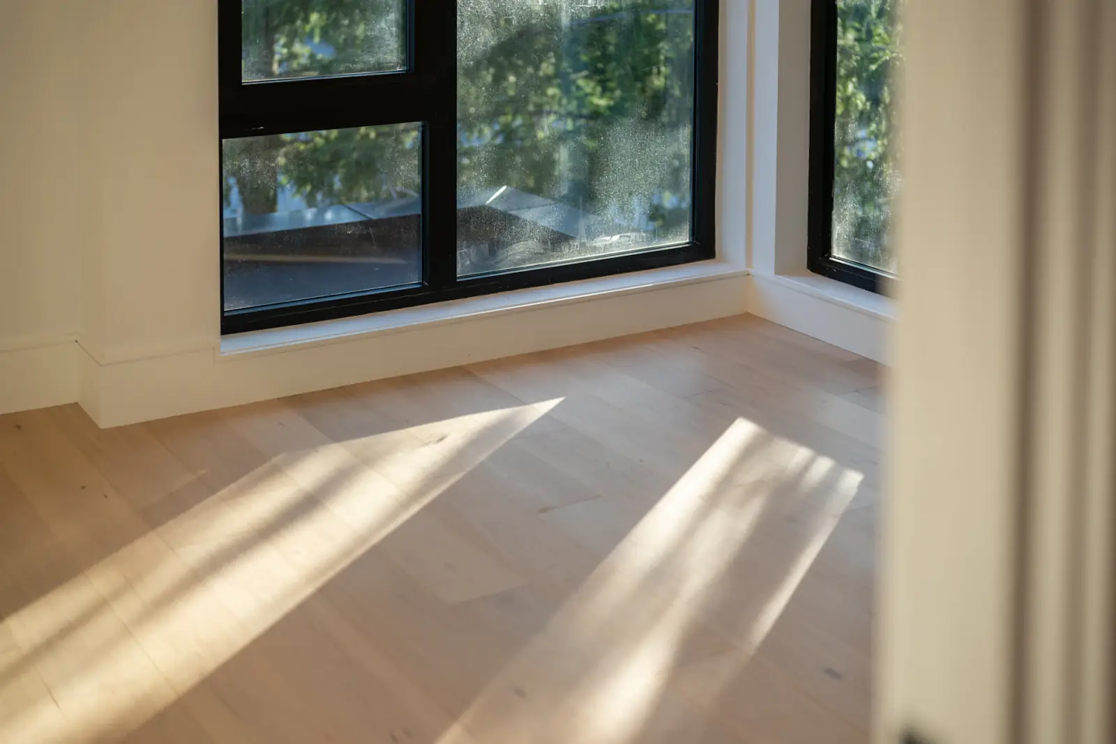 Lumière du matin rasant un parquet clair dans une pièce vide